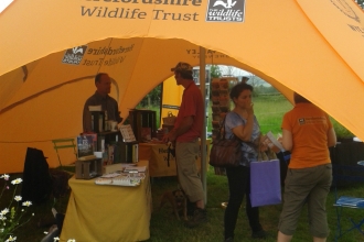 Staff, volunteers and members of the public chatting under a star tent