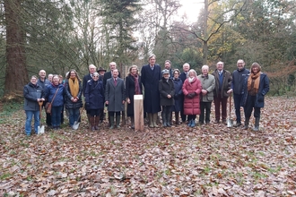 Group of people stood for photo in outdoor clothes in woodland in winter