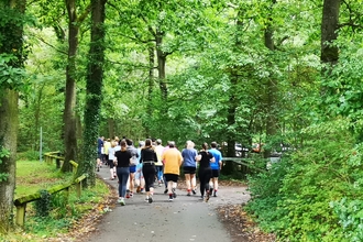 Group of runners running away from viewer in woodland setting