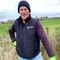 Man in outdoor wear stood smiling at camera in field