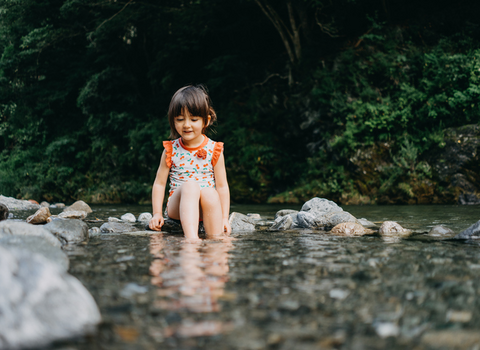 Girl sat on pebbles in river