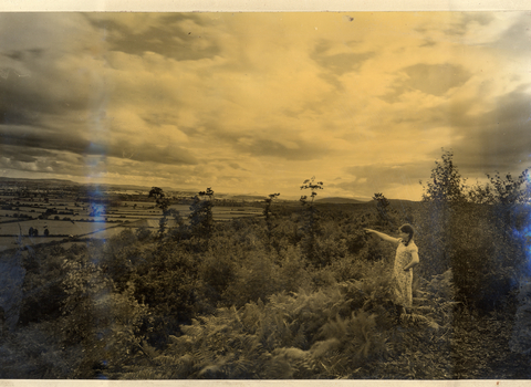 Old sepia photo of girl looking out over wooded landscape