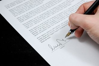 Paper with black printed text and hand signing beneath