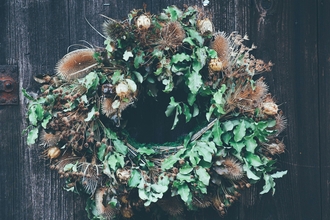 Wreath of natural greenery on dark wood door