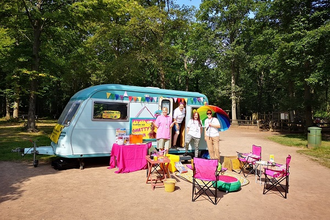 Caravan with bright deckchairs in front and small group of people