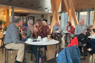 A dozen people sat at small tables talking animatedly in groups 