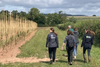 five people walking beside an arable field in the countryside