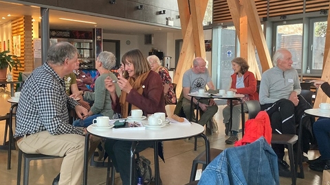 A dozen people sat at small tables talking animatedly in groups 