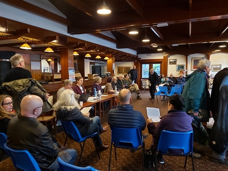 Room filled with people sat on blue chairs