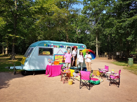 Caravan with bright deckchairs in front and small group of people