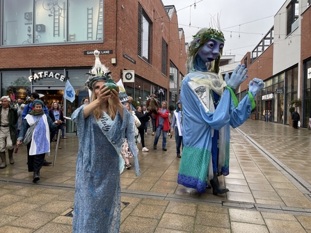 Huge puppet woman and lady in blue dress in city centre