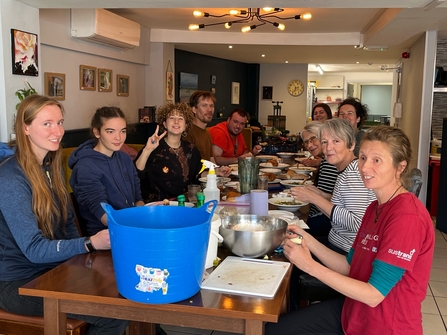 People sat around a long table preparing food