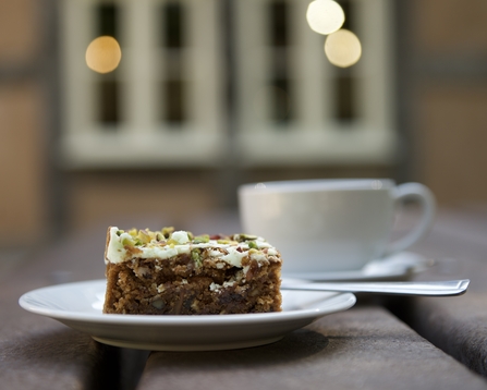 A piece of cake and coffee cup on a bench